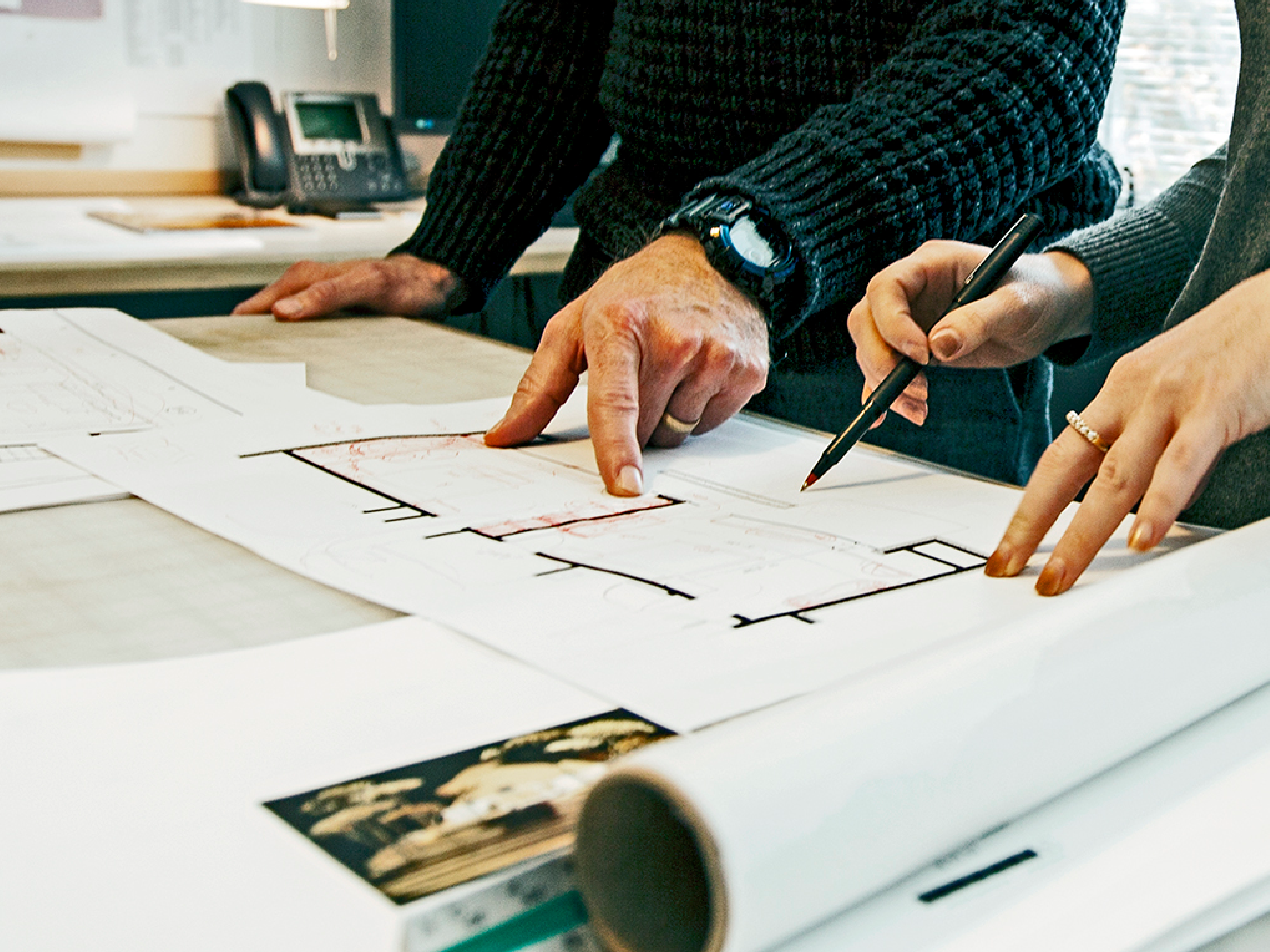Hands reviewing architectural drawings with annotations during design development