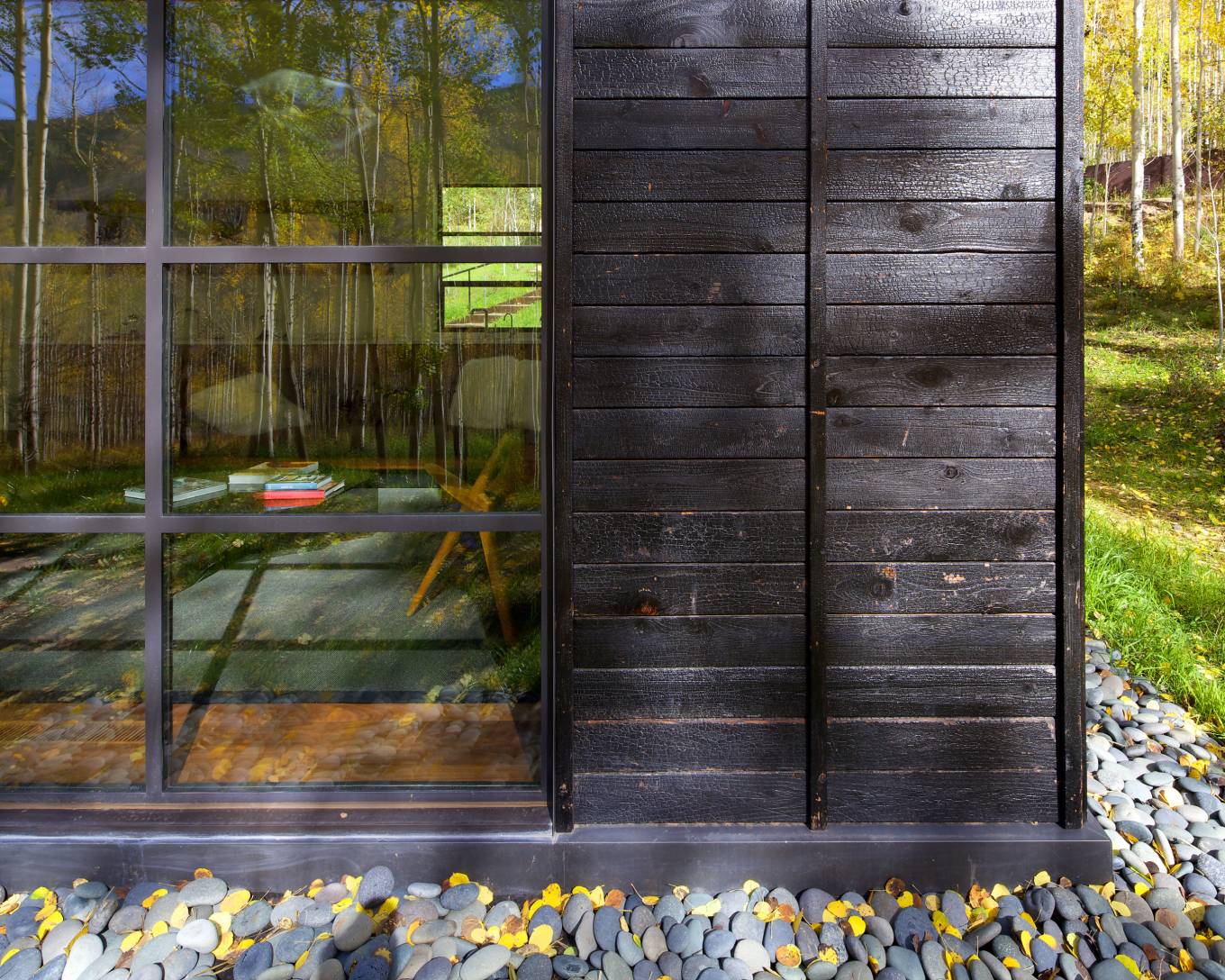he vertical battens on the charred cedar siding were chosen to relate to the immense verticality established by the trees.
